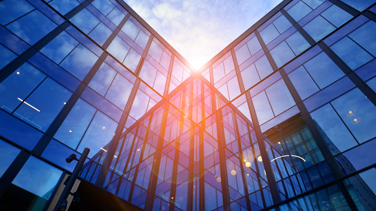 Glass Modern Building With Blue Sky Background. Low Angle View And Architecture Details. Urban Abstr Glass modern building with blue sky background. Low angle view and architecture details. Urban abstract - windows of glass office building in sunlight day.